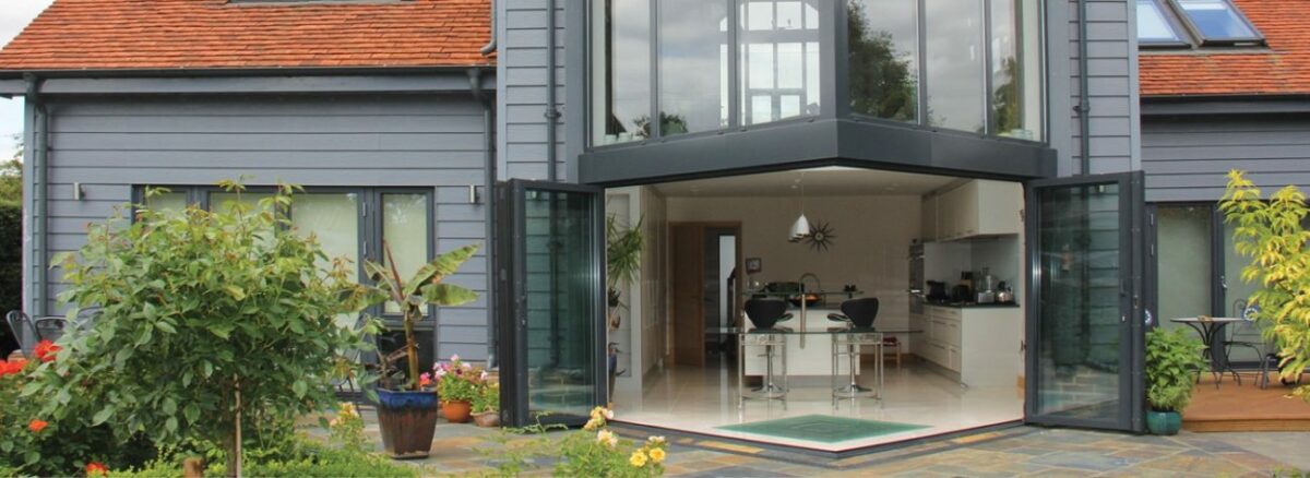 Modern Suffolk extension with award-winning bifold doors and glazing systems opening onto a paved garden area.