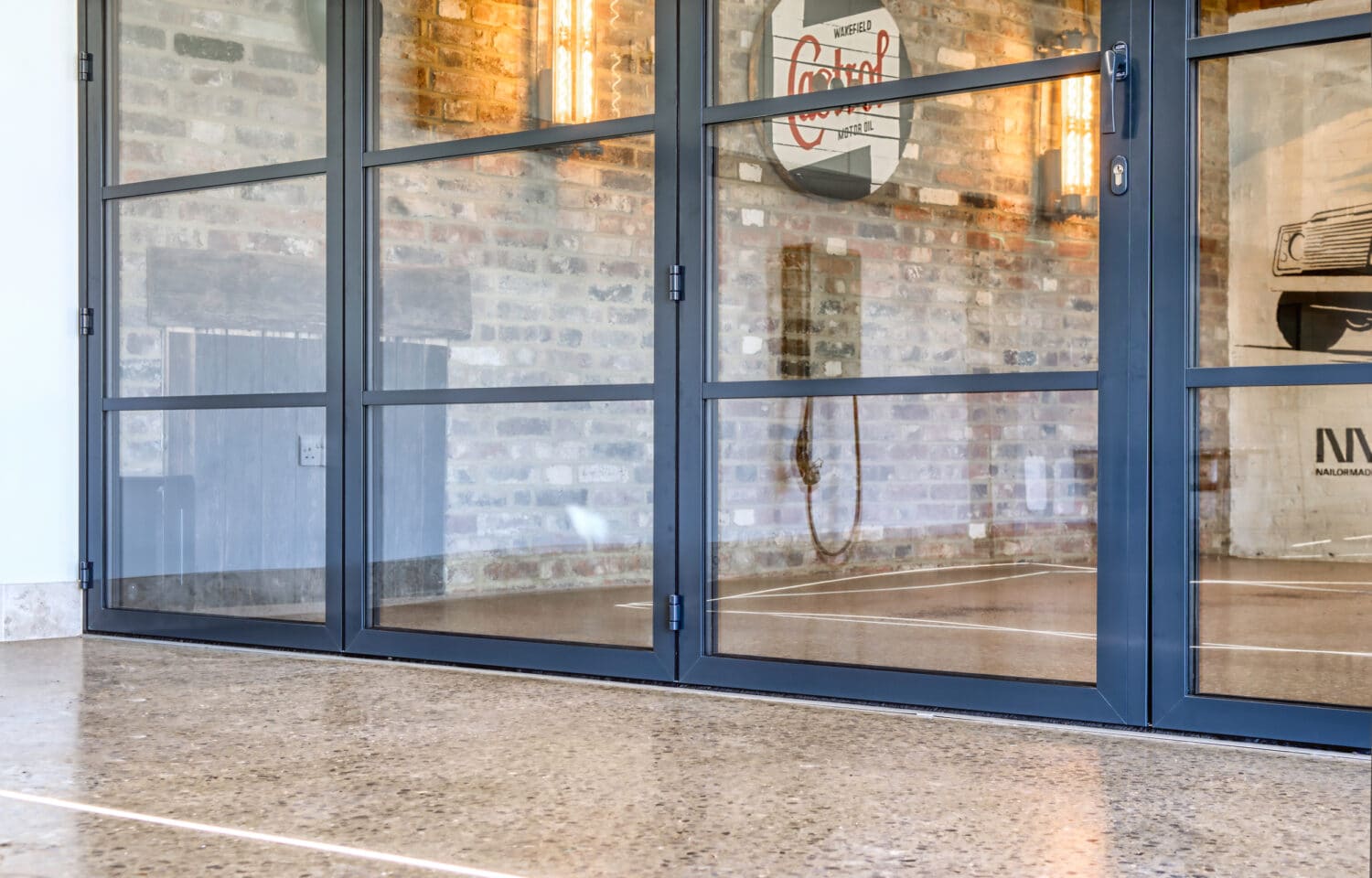 Sleek aluminium bifold doors with slim-profile frames open onto exposed brick, flooding the space with natural light and seamless indoor-outdoor connection.