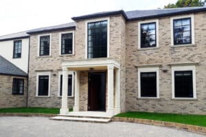 Two-story brick house with a central entrance, large windows, and a small porch supported by columns.