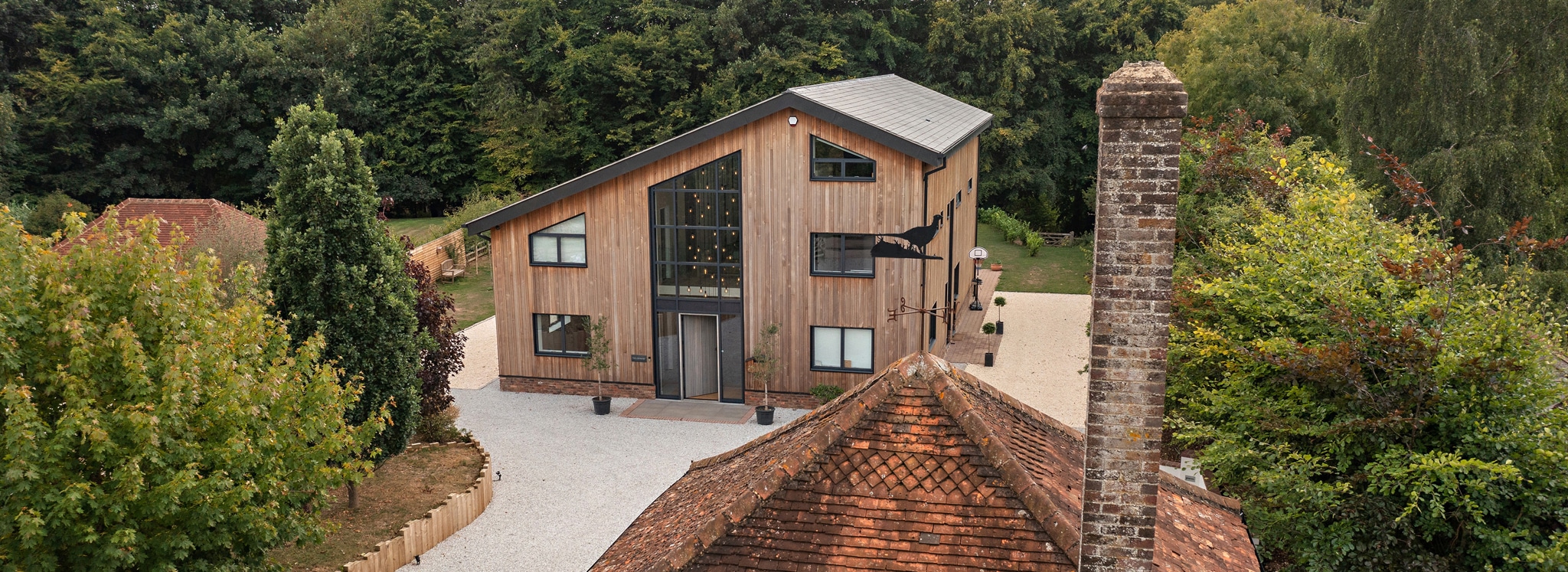 Contemporary barn conversion with extensive glazing, aluminium bifold doors, and slim-profile windows flooding the open-plan interior with natural light.