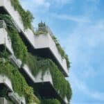 Credit: Towfiqu Barbhuiya A modern building with multiple balconies covered in lush green plants, set against a clear blue sky.