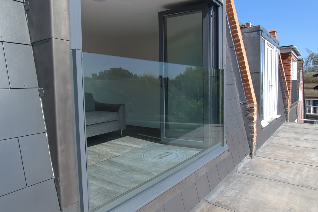 Modern rooftop terrace featuring frameless glass balustrade with contemporary sliding doors and minimalist aluminium framing, showcasing premium glazing solutions.