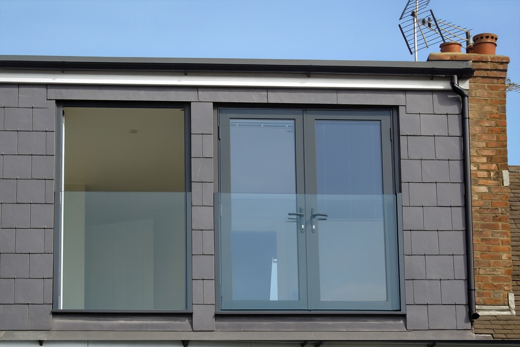 Modern grey aluminium sliding doors and window with slim frames overlooking coastal views, showcasing contemporary glazing design.