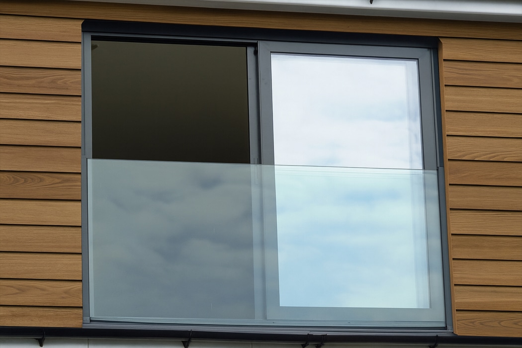 Modern aluminium sliding glass doors with frameless glass panels showcase sky views on wooden facade.