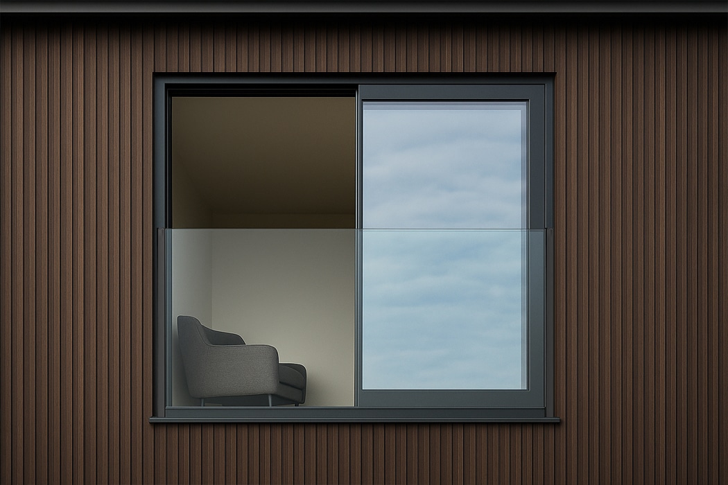 Modern interior with frameless glass Juliet balcony overlooking cloudy sky, featuring slim-profile aluminium frame and contemporary grey armchair.