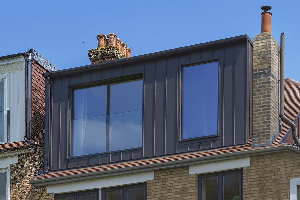 Modern dark aluminium framed glazing with slim-profile windows overlooking period brick buildings, exemplifying contemporary glass balustrade design.