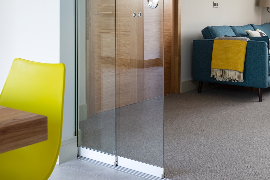 Frameless SF20 single glazed sliding door seamlessly separating modern living spaces with minimal aluminium frame design.
