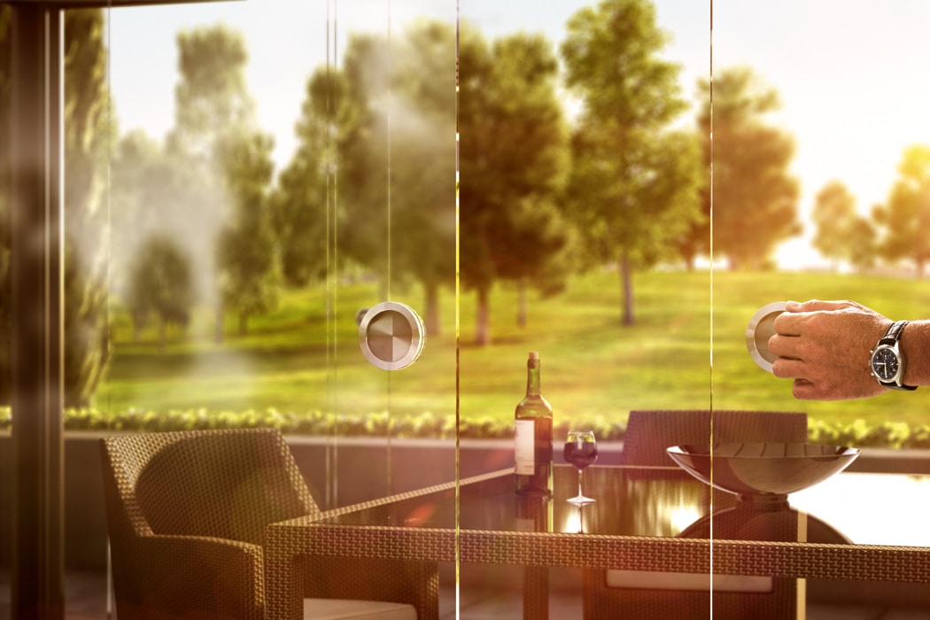 Man enjoying countryside views through frameless SF20 single glazed sliding doors, opening onto sunlit gardens and parkland.