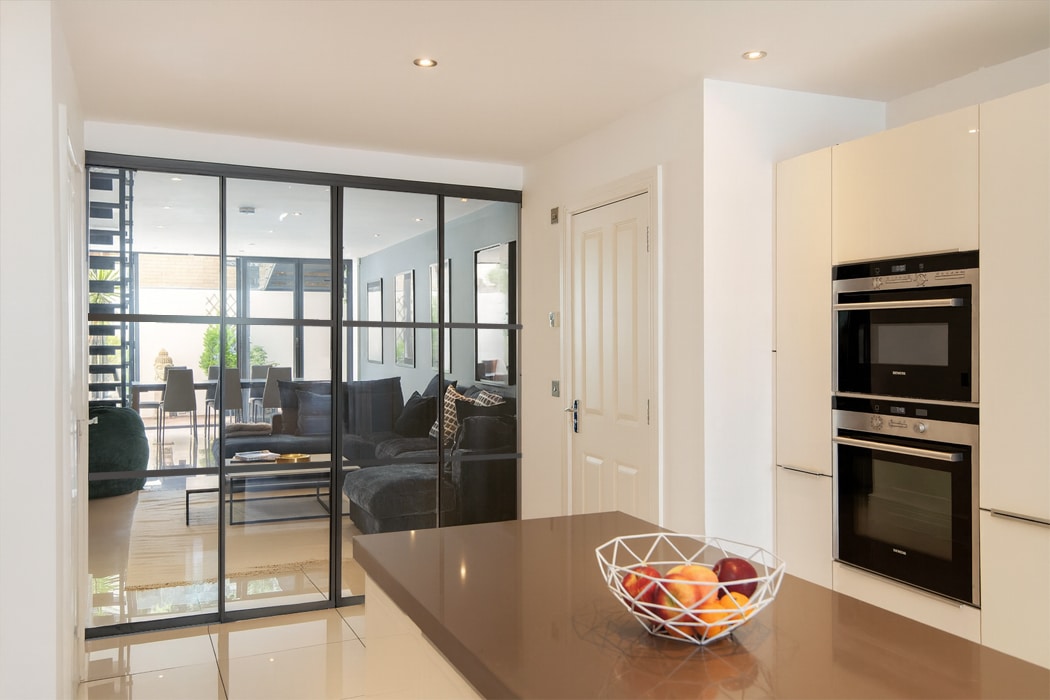 SF22 heritage sliding doors with slim aluminium frames opening kitchen to contemporary balcony space with city views.