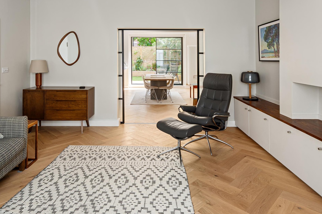 SF22 heritage sliding door with Art Deco-style glazing opens onto a garden, dividing a modern living room with period furniture and wooden flooring.