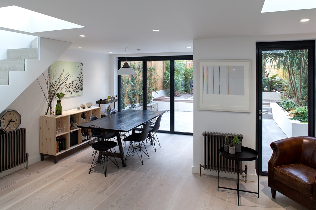 Modern West London extension with black aluminium bifold doors opening to garden, featuring contemporary dining space and natural light.
