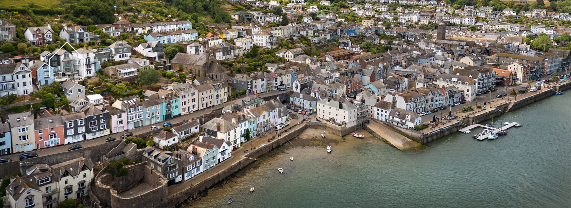 Aerial view of Dartmouth hillside revealing colourful waterfront homes with modern glazing maximising coastal views and natural light.