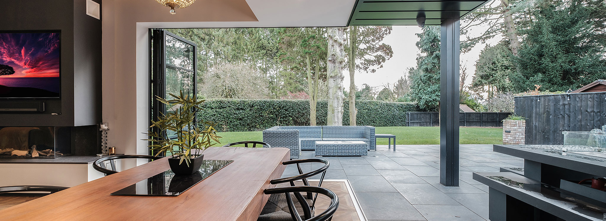 Modern open-plan living space with bifold doors seamlessly connecting interior to expansive garden and patio area.
