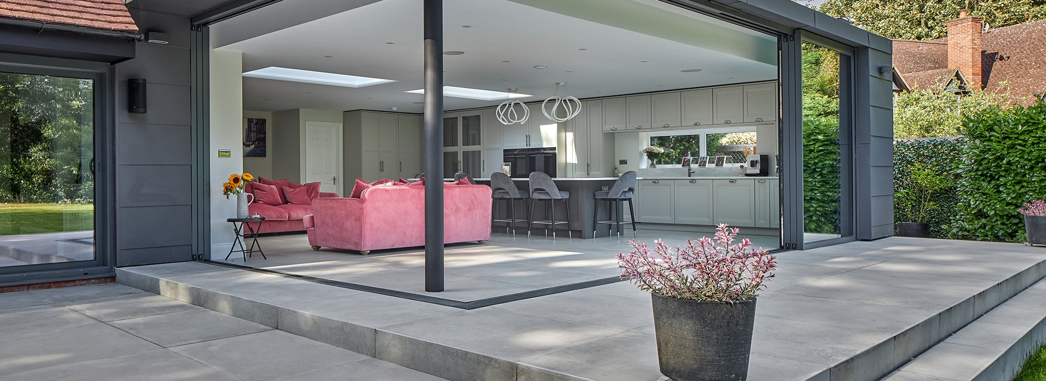Modern open-plan kitchen and living space with seamless aluminium sliding doors creating a flush transition between indoor and outdoor areas.