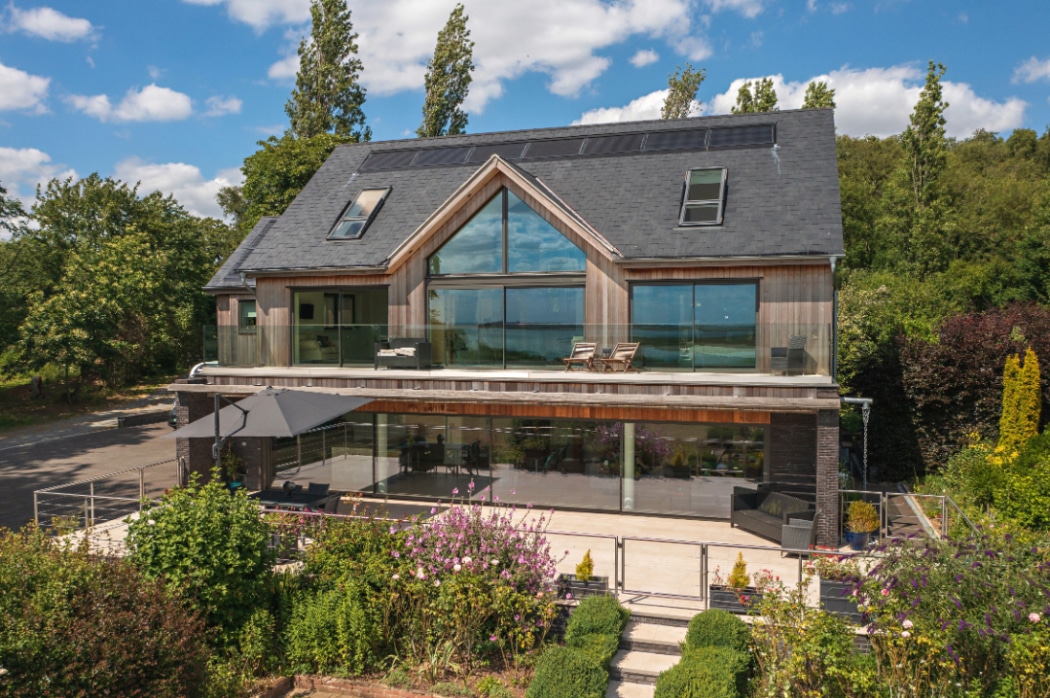 Contemporary riverside Essex home featuring expansive 4 panel sliding glass doors flooding the interior with natural light