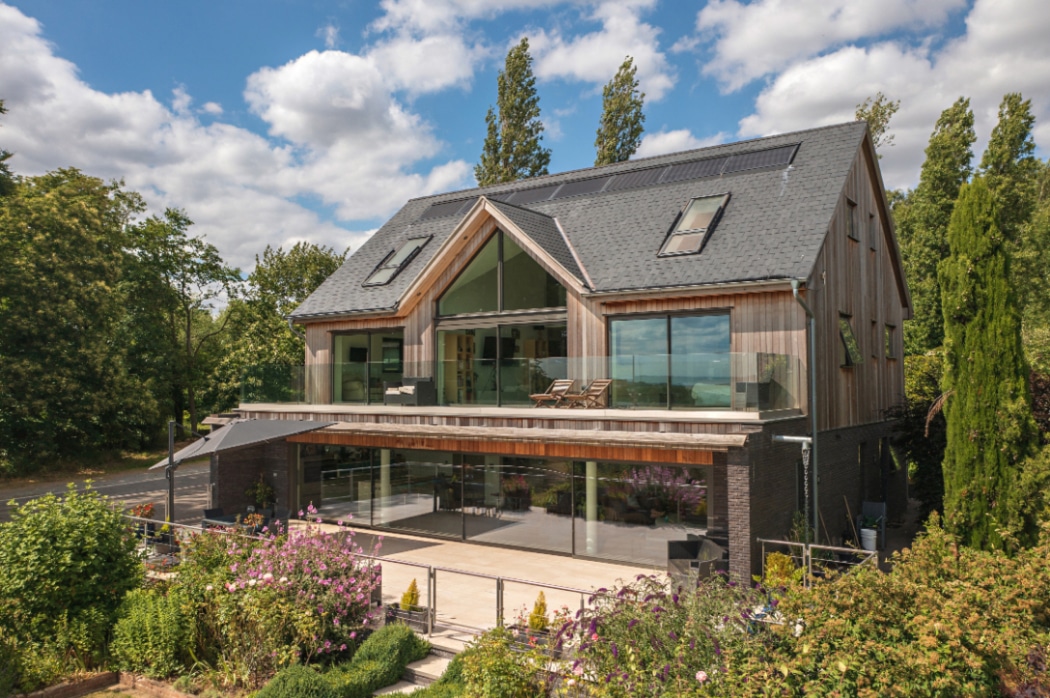 Contemporary riverside home featuring expansive 4 panel sliding glass doors opening onto a terrace, flooding the space with natural light.