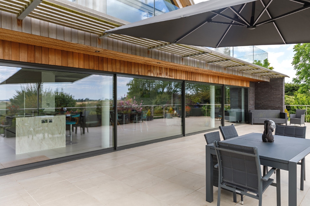 Modern 4 panel sliding glass doors open a riverside home to expansive terrace views and natural light