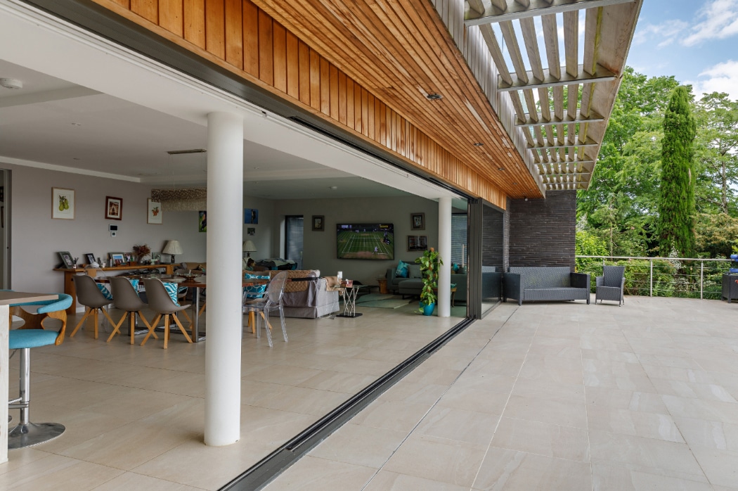 4 panel sliding glass door opening onto a spacious patio at a contemporary riverside home in Essex, flooded with natural light