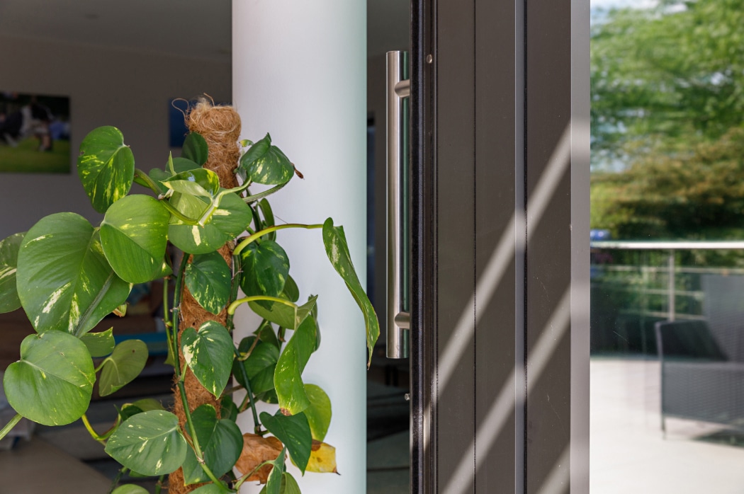 Modern sliding glass door opens onto a riverside garden, flooding contemporary Essex home with natural light