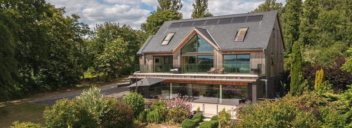 Modern riverside home in Essex with extensive glazing, bifold doors, and sliding glass panels maximising natural light and countryside views.