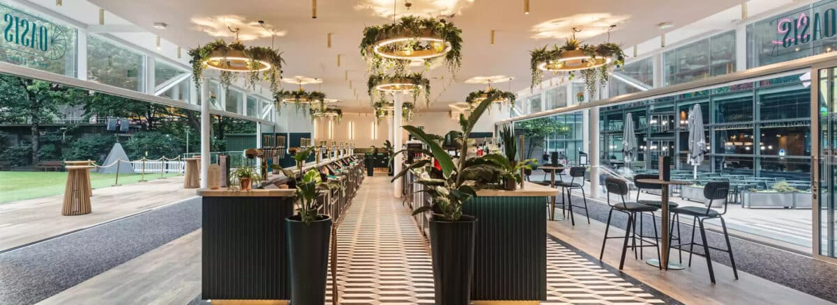 Modern oasis bar with floor-to-ceiling glazing, hanging greenery, and contemporary interior design showcasing award-winning glazing specialists' work.
