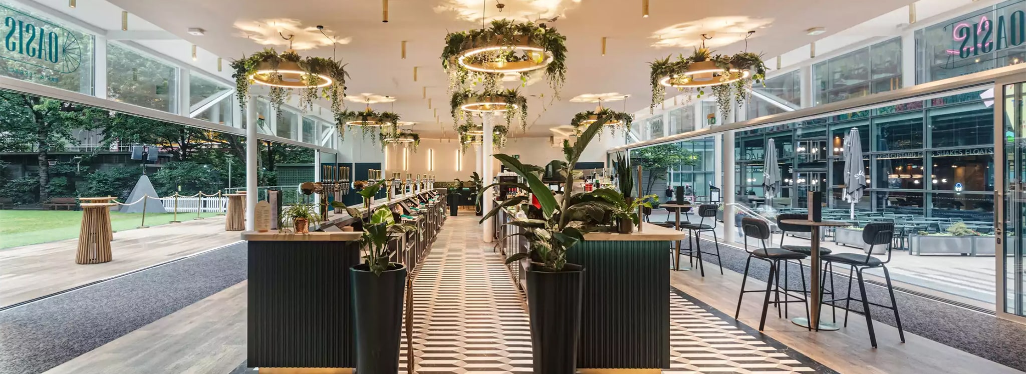 Modern oasis bar with floor-to-ceiling glazing, hanging greenery, and contemporary interior design showcasing award-winning glazing specialists' work.